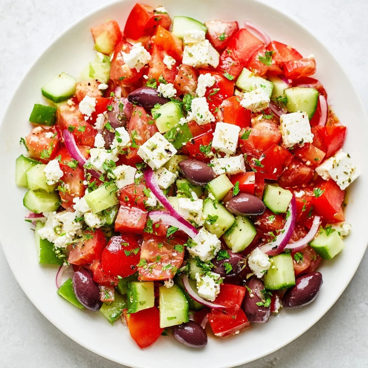 Vibrant Mediterranean Salad, boasting juicy tomatoes, creamy feta, and Kalamata olives tossed in olive oil.
