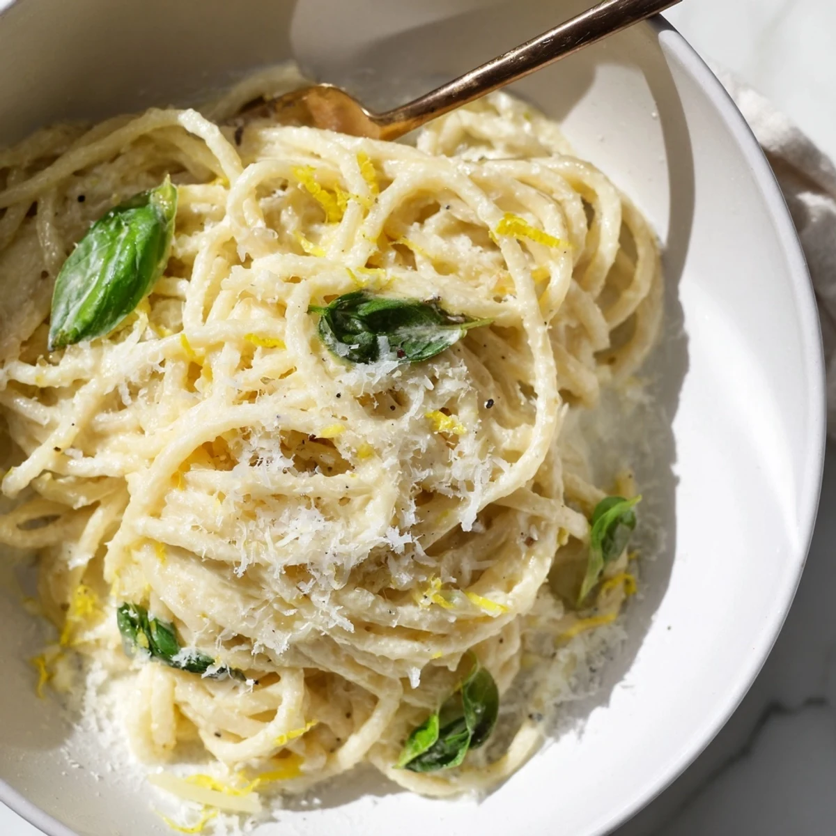 A warm bowl of Lemon Ricotta Pasta with spaghetti coated in creamy sauce, garnished with fresh basil and extra lemon zest.