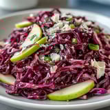 Freshly tossed Red Cabbage Coleslaw With Apple and Parmesan, with a tangy vinaigrette glistening on colorful, crunchy salad ingredients.  