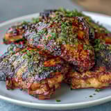 Honey garlic grilled chicken thighs sizzling on the barbecue with a sticky glaze and golden char marks.  