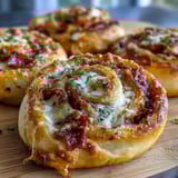 Baked puff pastry spirals stuffed with marinara, melted cheese, and savory pepperoni, ideal for parties or appetizers.  
