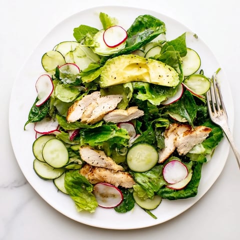 Freshly grilled chicken slices rest atop a vibrant bed of Spring Detox Chicken Salad with crisp cucumber, radish, and avocado.  