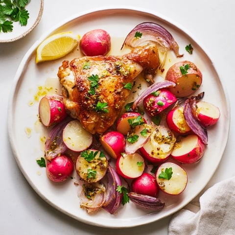 Juicy roasted chicken thighs and caramelized radishes on a golden sheet pan, topped with fresh parsley and lemon zest.