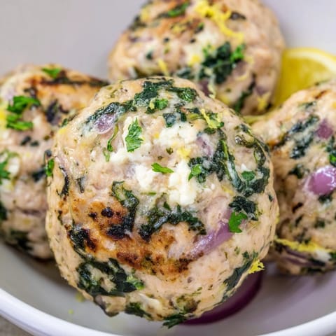 These baked spinach feta turkey meatballs, with a lemon garnish, look perfect for a flavorful Greek meal.
