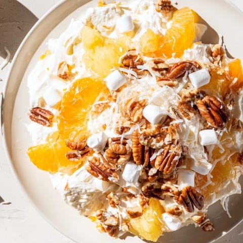 This refreshing, chilled Elevated Ambrosia Salad features bourbon-infused whipped cream and colorful fruit.