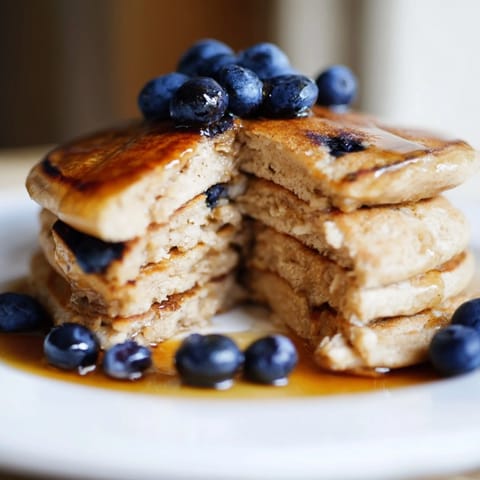 A stack of fluffy Brown Banana Pancakes topped with creamy Greek yogurt and chopped nuts.  