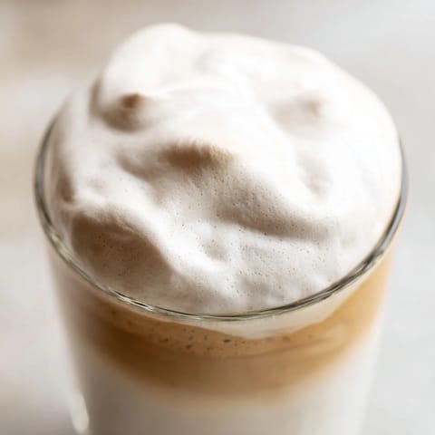 A spoonful of creamy whipped Dalgona coffee is added to a hot latte.