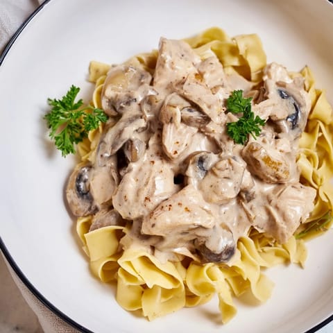 A comforting plate of Chicken and Mushroom Stroganoff, featuring sautéed mushrooms and juicy chicken in a rich, savory sauce, garnished with fresh parsley.