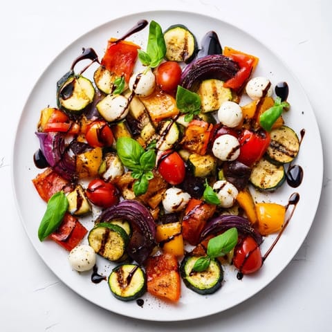 A warm Roasted Veggie Caprese Salad featuring mozzarella pearls and fresh basil leaves.
