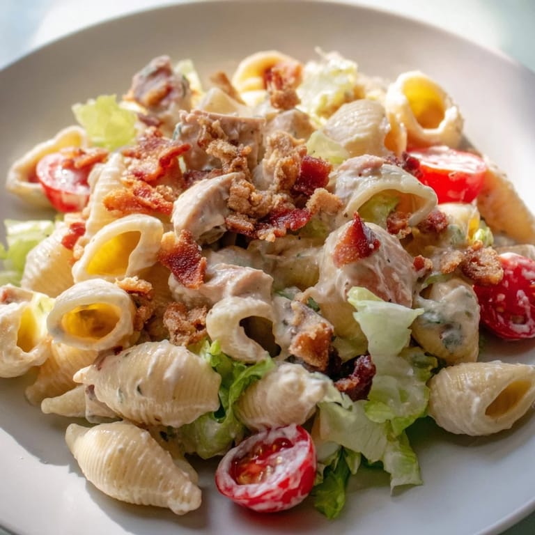 A close-up of BLT Chicken Pasta Salad with grilled chicken, halved cherry tomatoes, and a light, creamy dressing.  