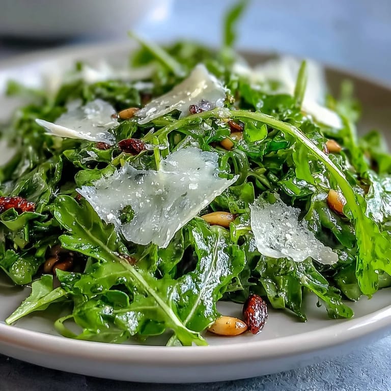 Bright lemon vinaigrette coats tender arugula leaves, topped with nutty Parmesan shavings for a crisp, flavorful salad experience.